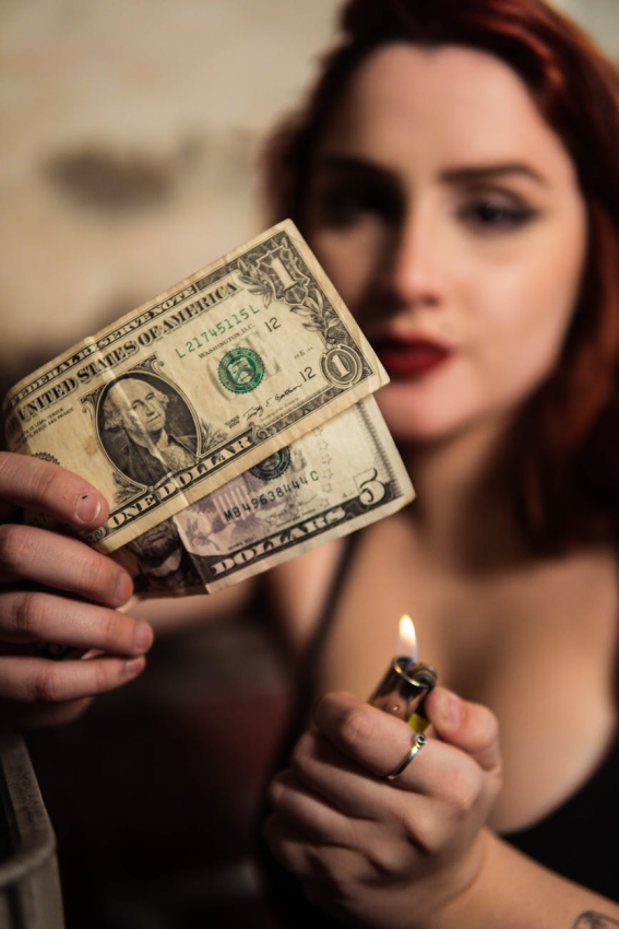 woman holding dollar bills and a lighter