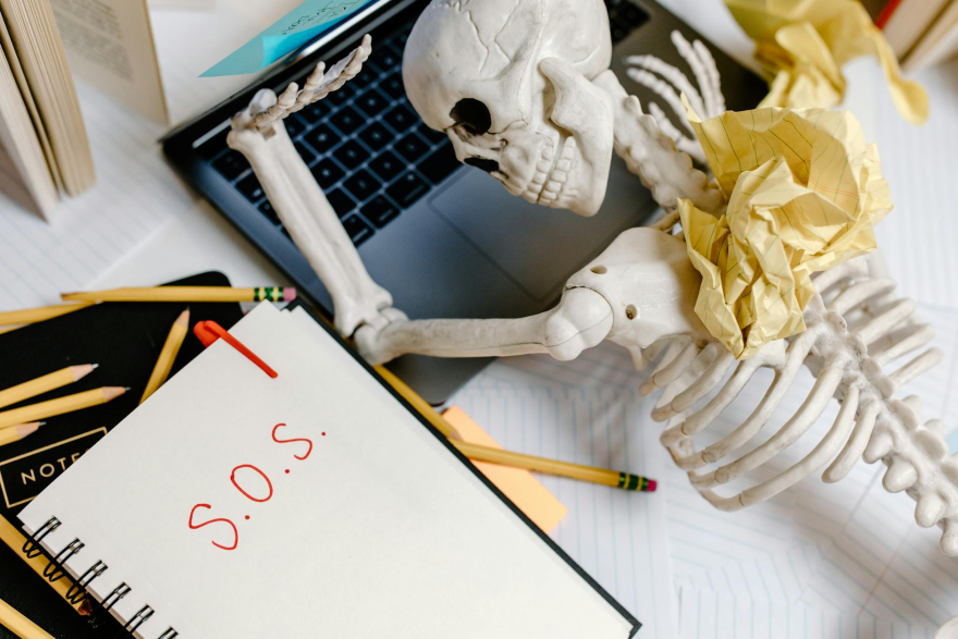 white skeleton figurine on white table beside a laptop