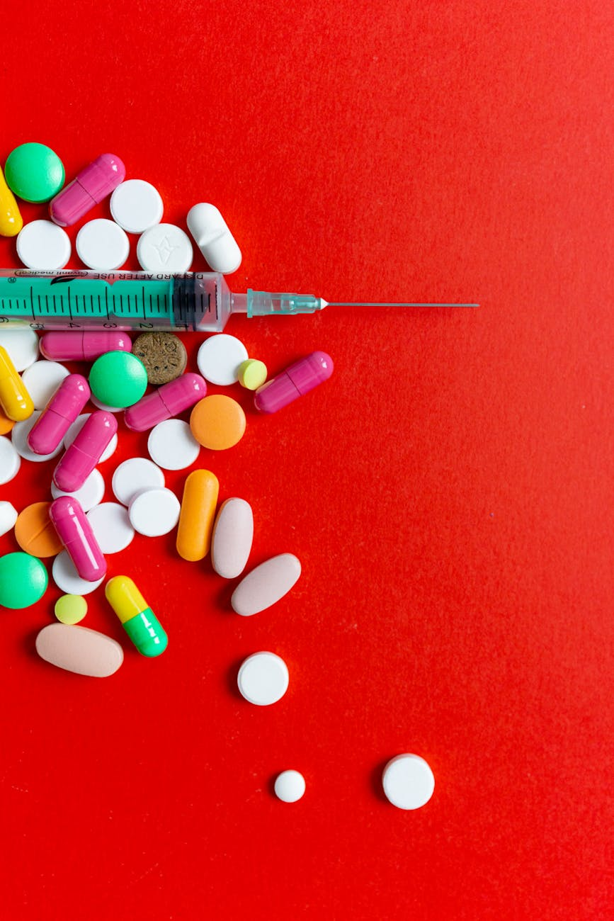 pills and a syringe on a red surface