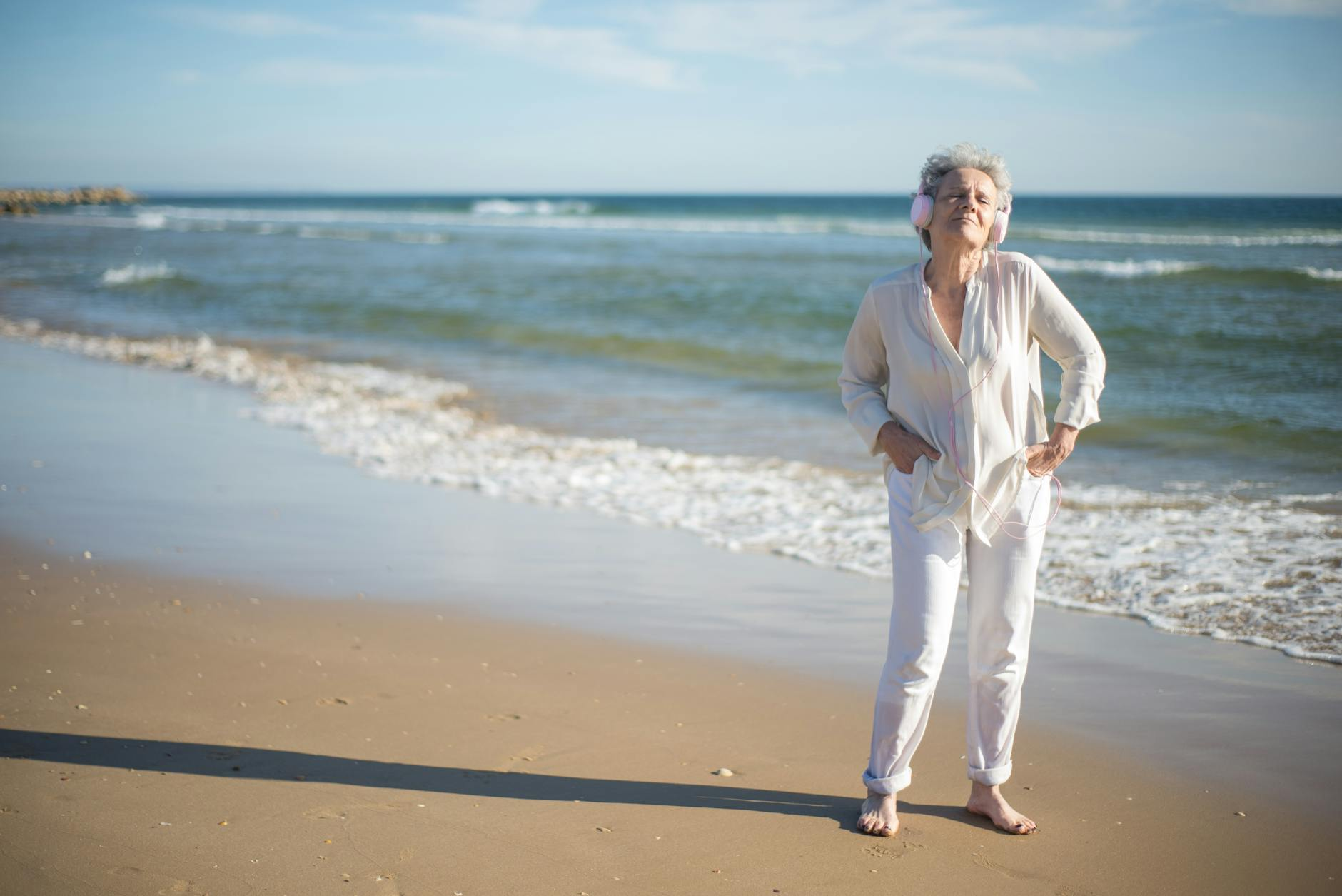 elderly woman standing on shore while listening to music
