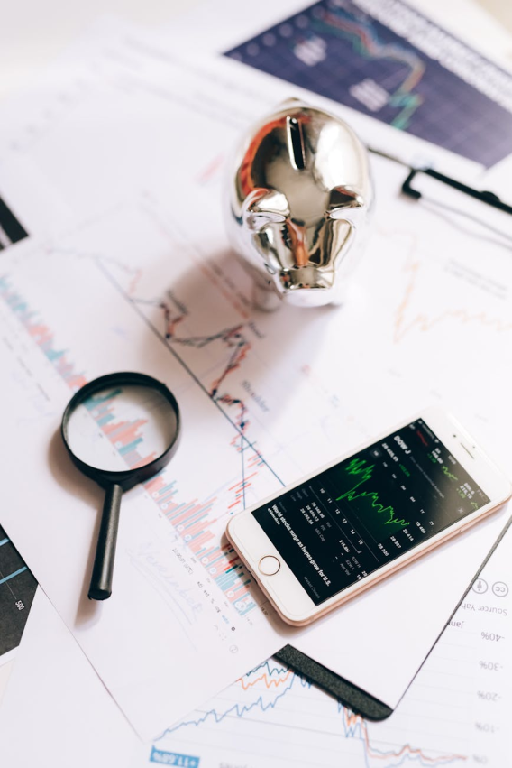 a silver piggy bank near the magnifying glass and smartphone