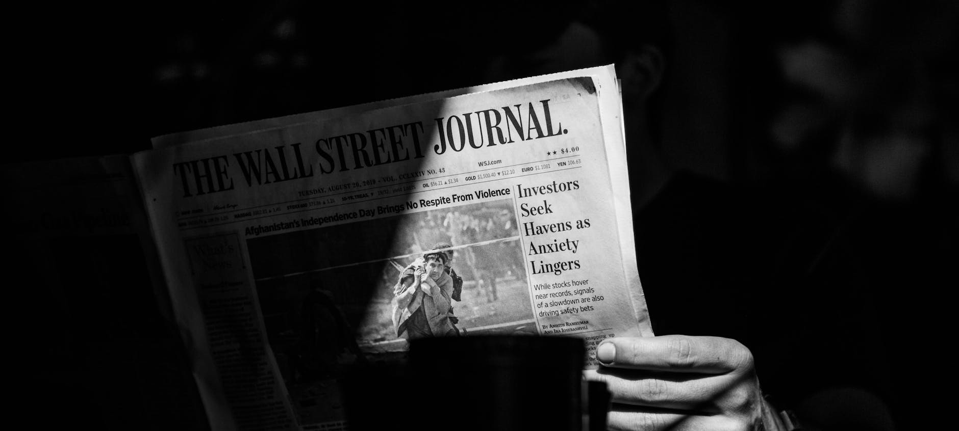 grayscale photo of a person holding a newspaper