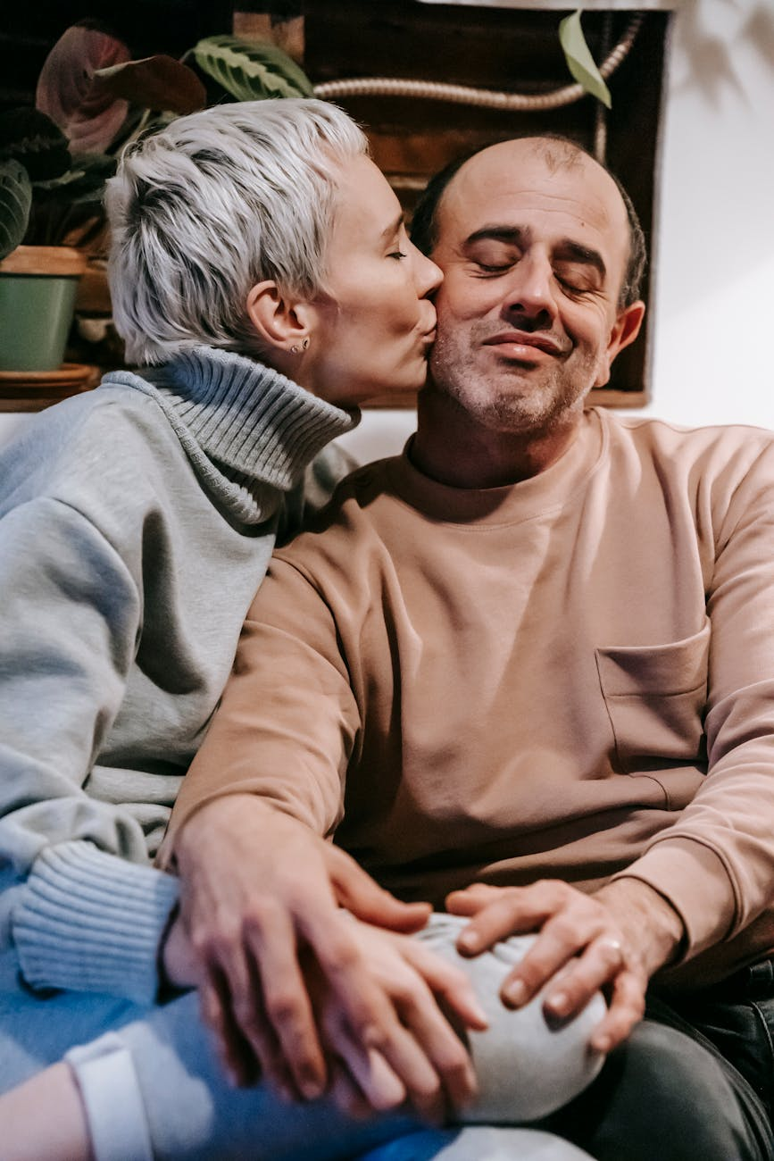 loving woman kissing cheek of man sitting closely