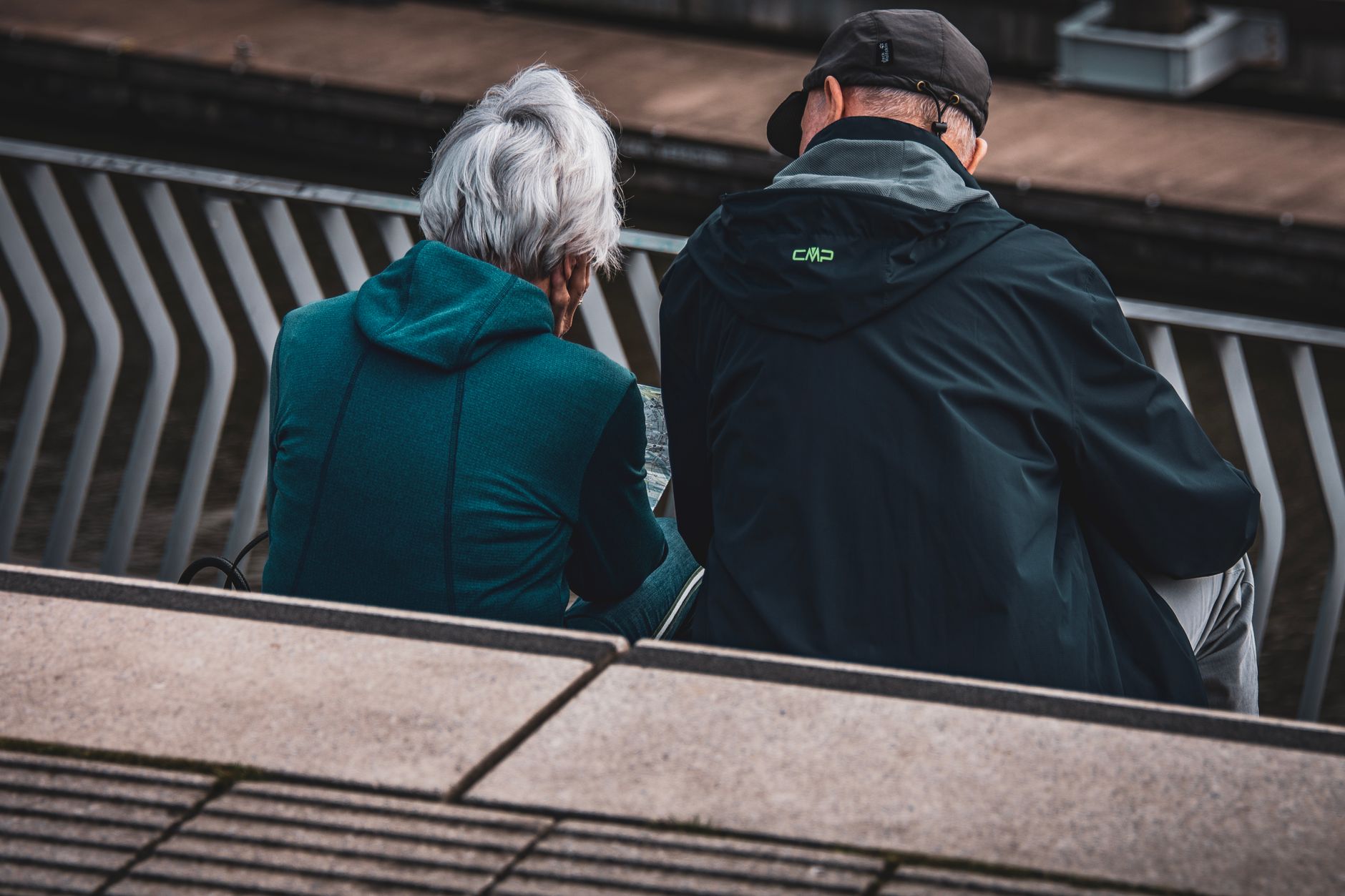 back view of an elderly couple sitting on the steps in city