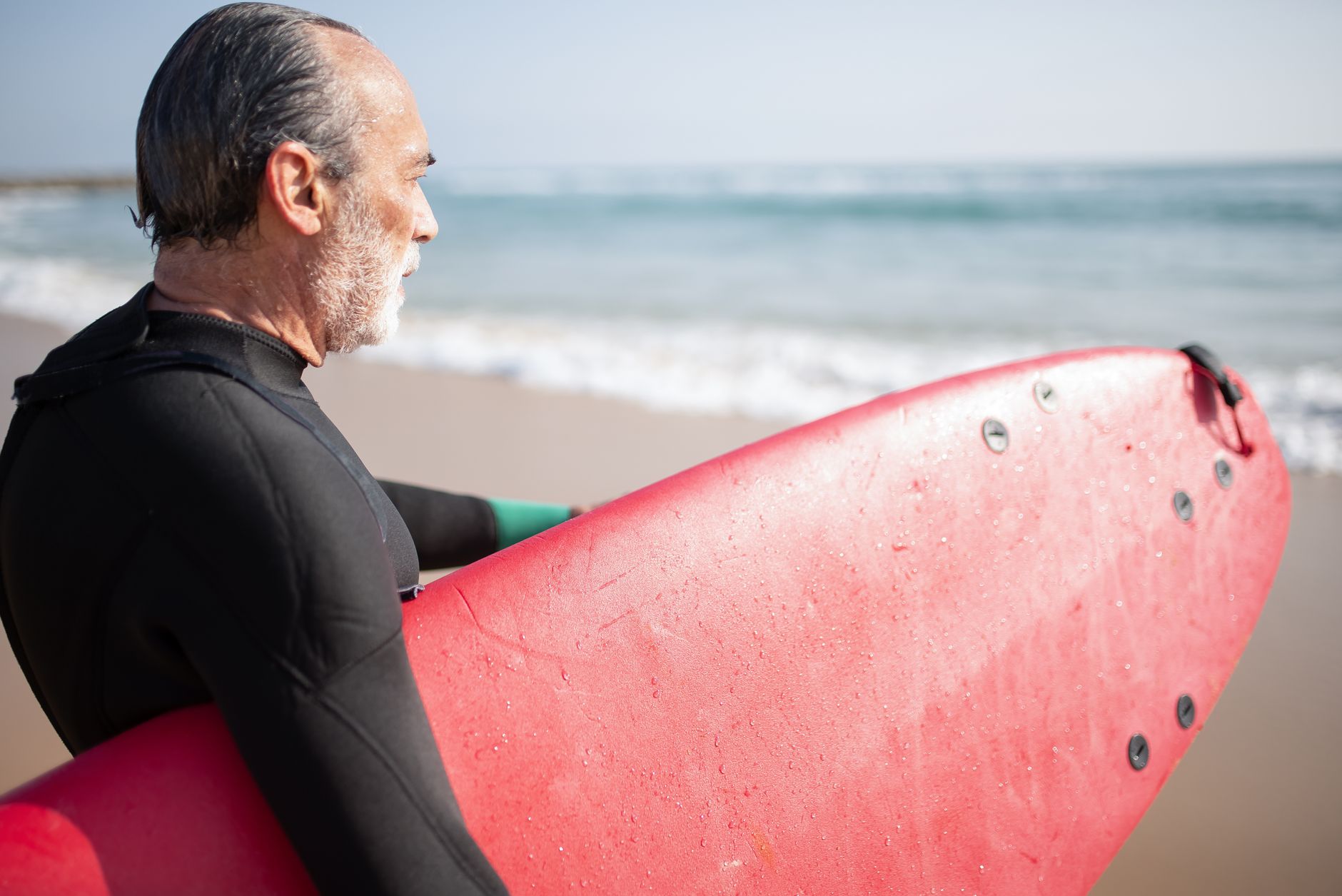 an elderly man carrying a surfboard