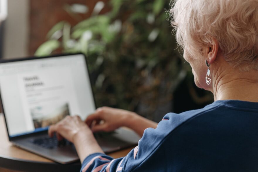 side view shot of woman in blue sweater typing on the keyboard of a laptop