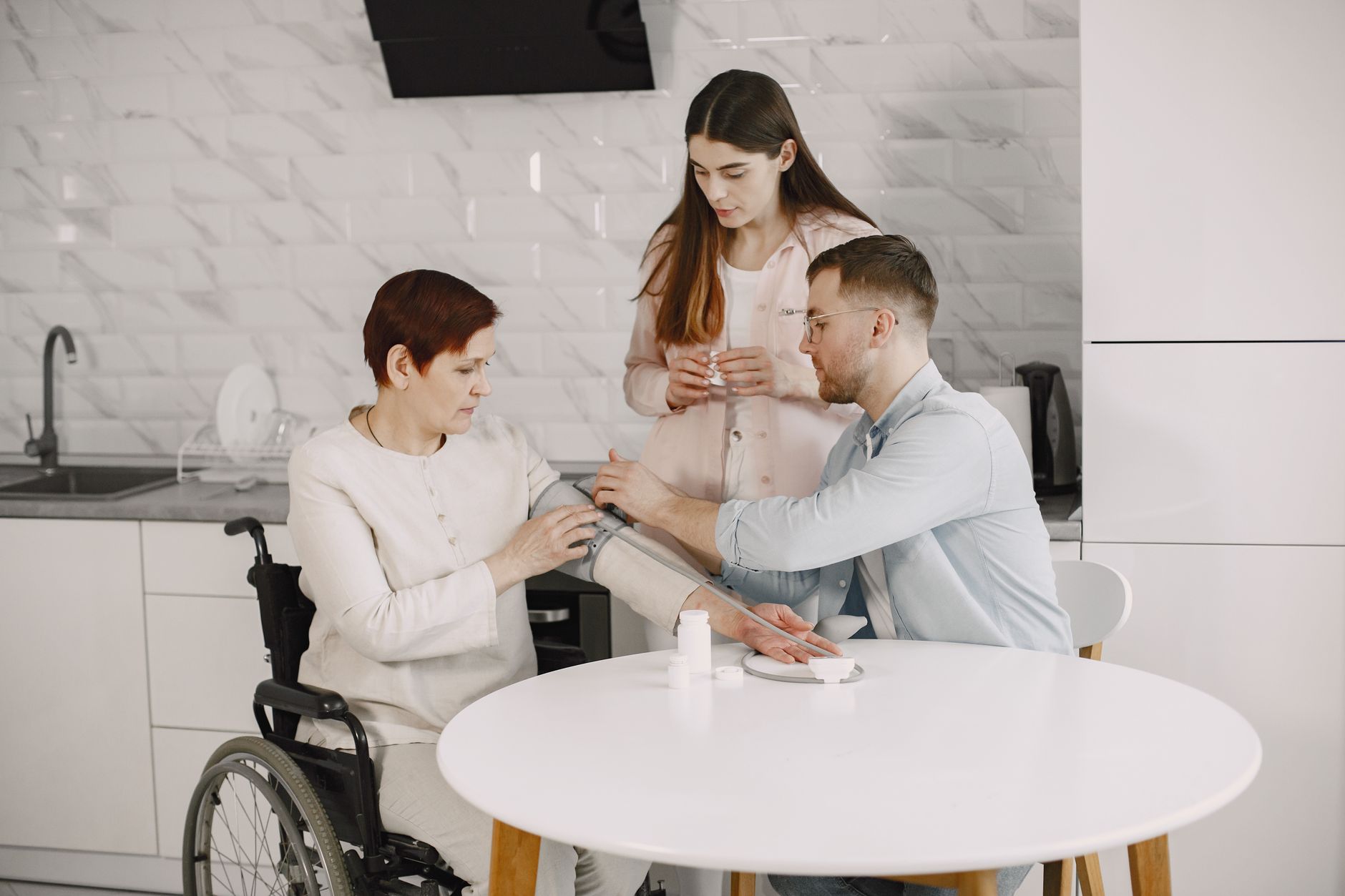 a man monitoring the blood pressure of the woman sitting on the wheelchair using sphygmomanometer