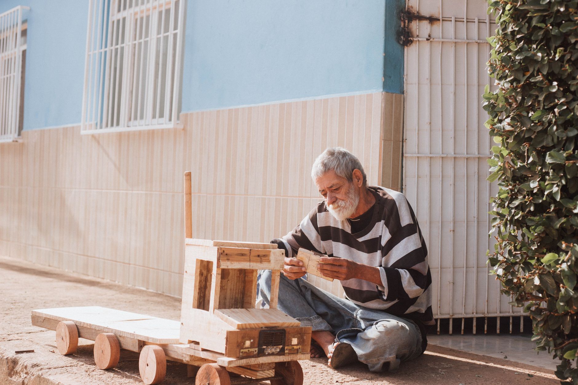 elderly man crafting wooden toy outdoors